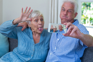 Senior couple making faces while taking selfie at home