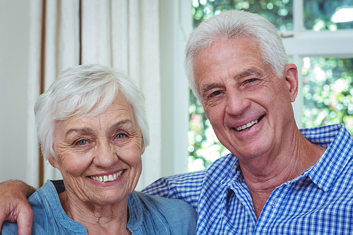 Close-up portrait of happy senior couple with arm around at home