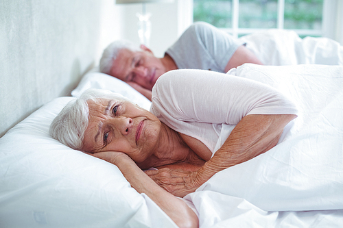 Retired couple relaxing on bed at home