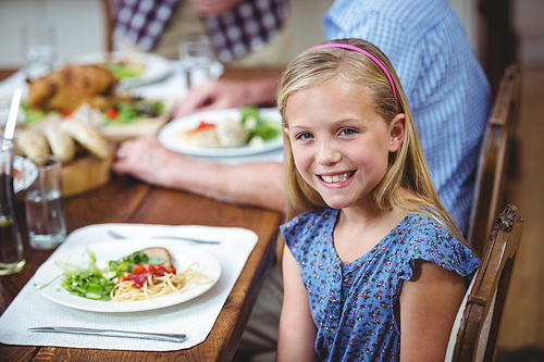 Portrait of smiling girl sitting at dining table with family
