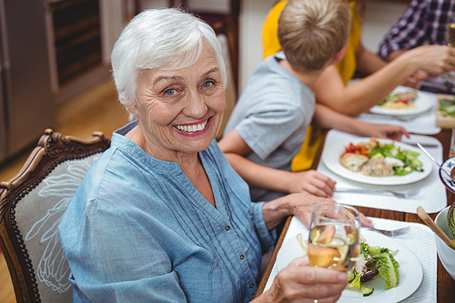 Portrait of smiling granny sitting at dining table with family