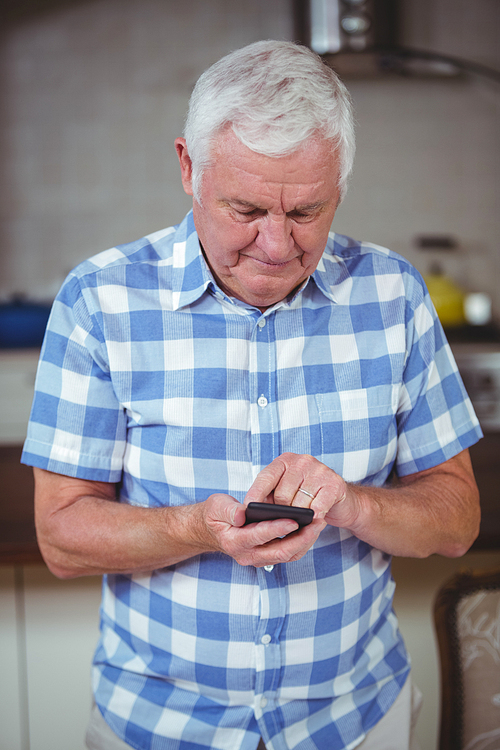 Senior man text messaging at home