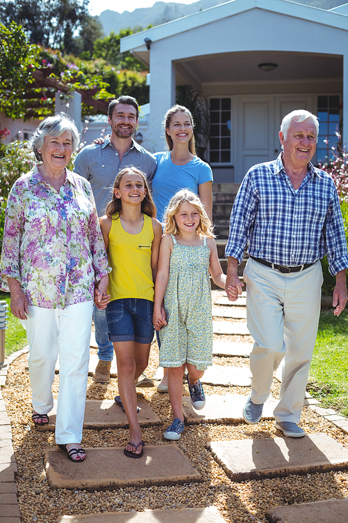 Happy multi-generation family walking on footpath outside house