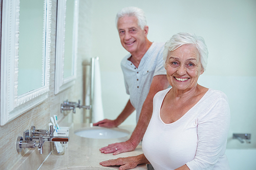 Portrait of senior couple standing by mirror in bathroom