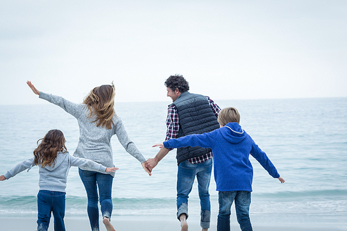 Rear view of children enjoying with parents at sea shore