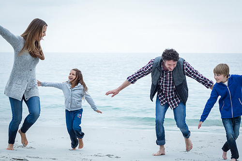 Happy family playing at sea shore against sky