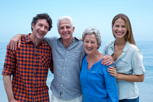 Portrait of cheerful family by sea against blue sky