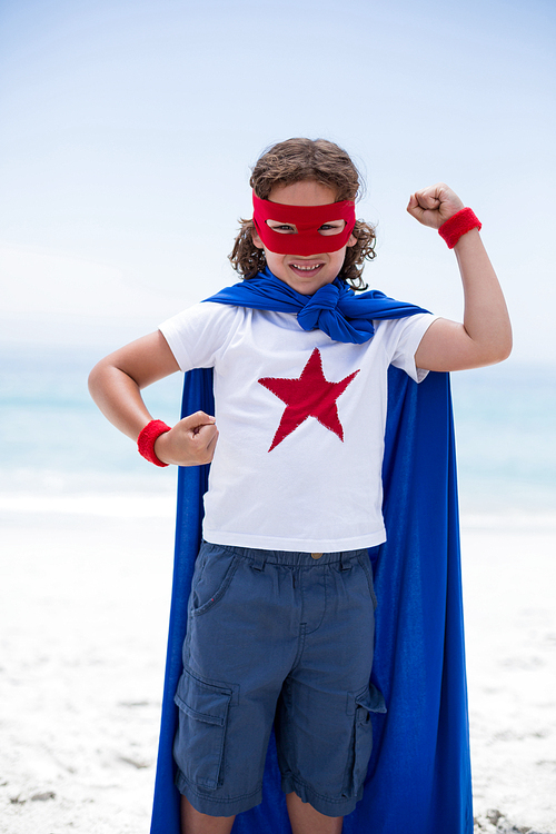 Portrait of boy in superhero costume standing at sea shore against sky