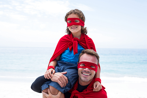 Portrait of father and son in superhero costume enjoying at sea shore