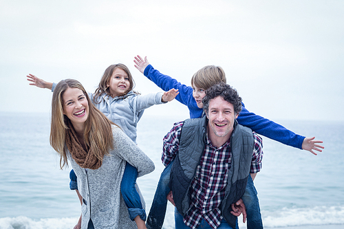 Happy parents carrying children and enjoying at sea shore