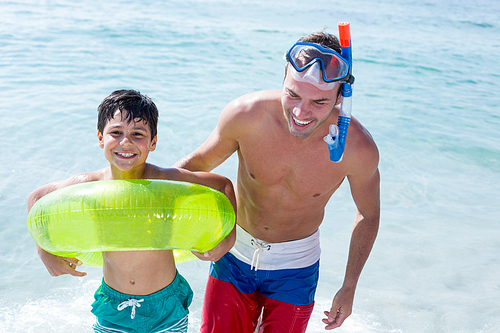 Happy family with swimming ring standing in sea at beach