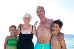 Portriat of grandparents with grandchildren standing on sea shroe at beach