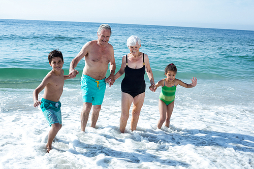 Happy grandchildren enjoying with grandparents at beach