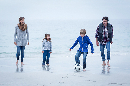 Happy family playing soccer at sea shore