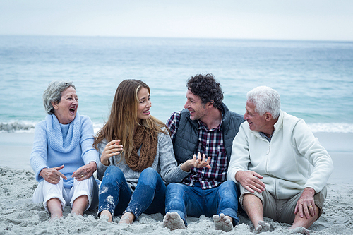 Smiling family sitting at sea shore against sky