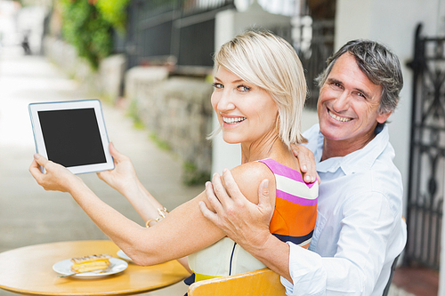 Rear view portrait of couple with tablet at cafe