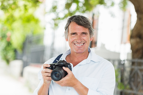 Portrait of happy man with camera in city