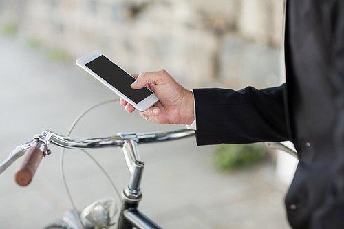 Midsection of businessman using cellphone with bicycle in city