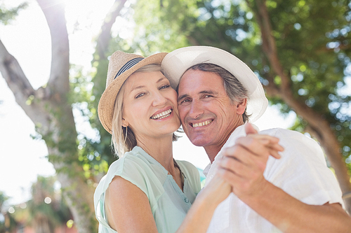 Portrait of happy couple holding hands against trees