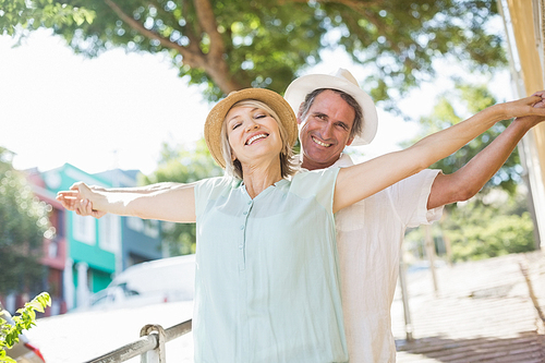 Happy couple with arms outstretched in city