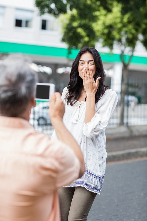 Rear view of man photograph happy woman blow  in city