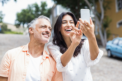 Happy woman with man taking selfie in city