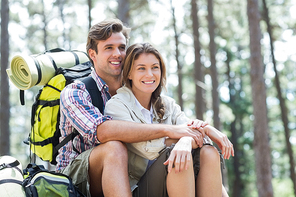 Happy couple embracing and sitting in forest during hiking