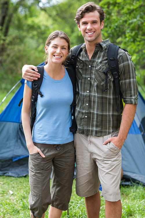 Portrait of happy young couple standing against tent in forest