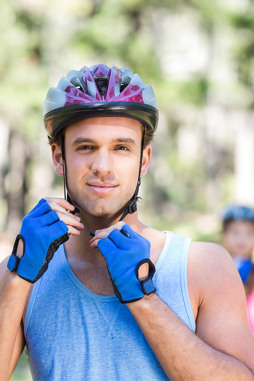 Portrait of young man wearing helmet against tree at forest