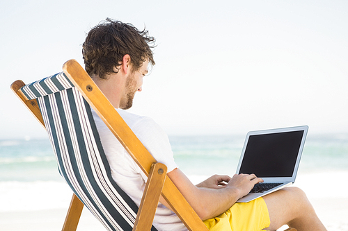 Man relaxing and using laptop on the beach