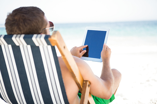 Man relaxing and using tablet on the beach