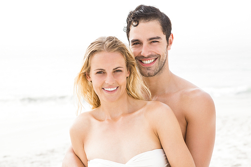 Happy couple embracing on the beach on a sunny day