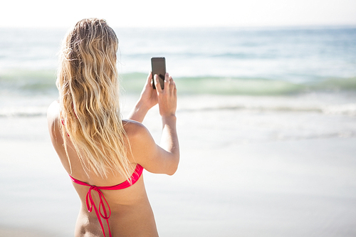 Blonde woman taking a selfie on the beach