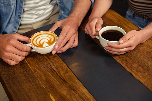 Close-up of couple holding coffee in a coffee shop