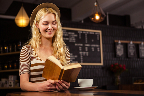 Smiling woman reading a book in a coffee shop