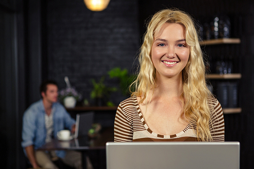 Smiling woman using laptop in coffee shop