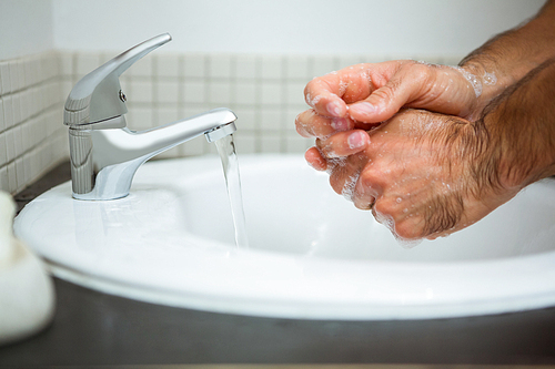 Man washing hands in bathroom washbasin