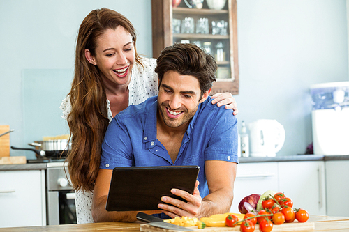 Happy young couple using digital tablet in kitchen