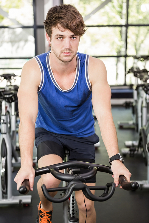 Man working out on exercise bike at spinning class in gym
