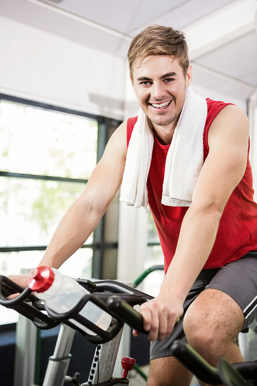 Portrait of man working out on exercise bike at spinning class in gym
