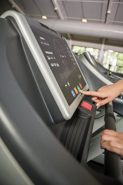 Hand of a person setting control panel of treadmill in gym
