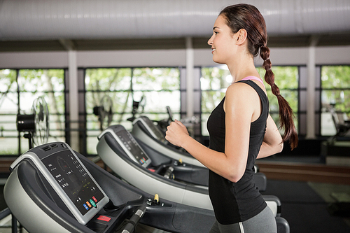 Happy woman jogging on treadmill at gym