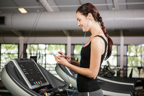Woman listening to music on treadmill at gym