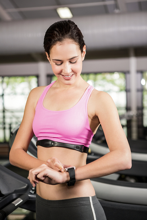 Woman using smart watch on treadmill at gym