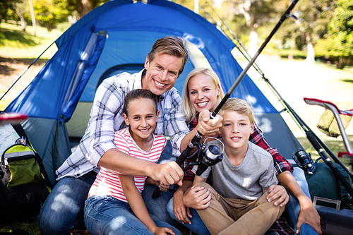 Family on a camping trip fishing outside their tent