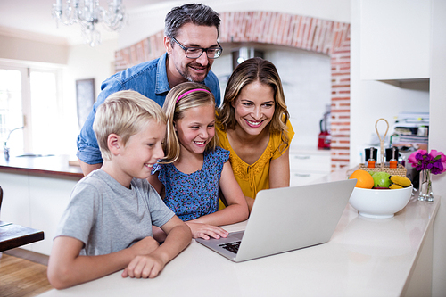 Parents and kids using laptop in kitchen at home