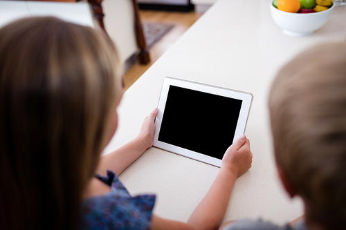 Siblings using digital tablet at home