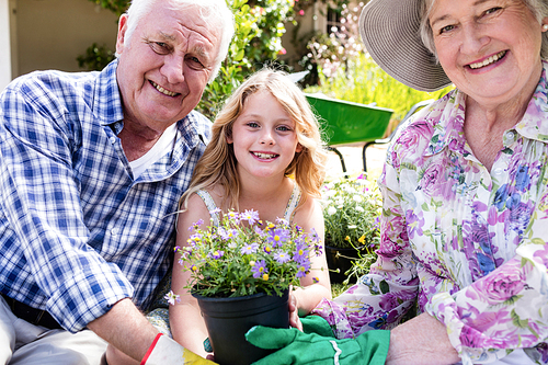 Portrait of grandparents and granddaughter holding flower pot in the garden
