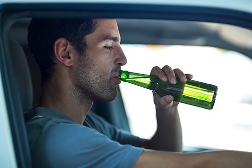 Close-up of man drinking alcohol while sitting in car