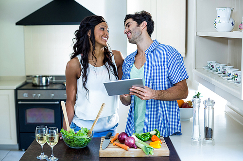 Young couple using digital tablet in kitchen at home